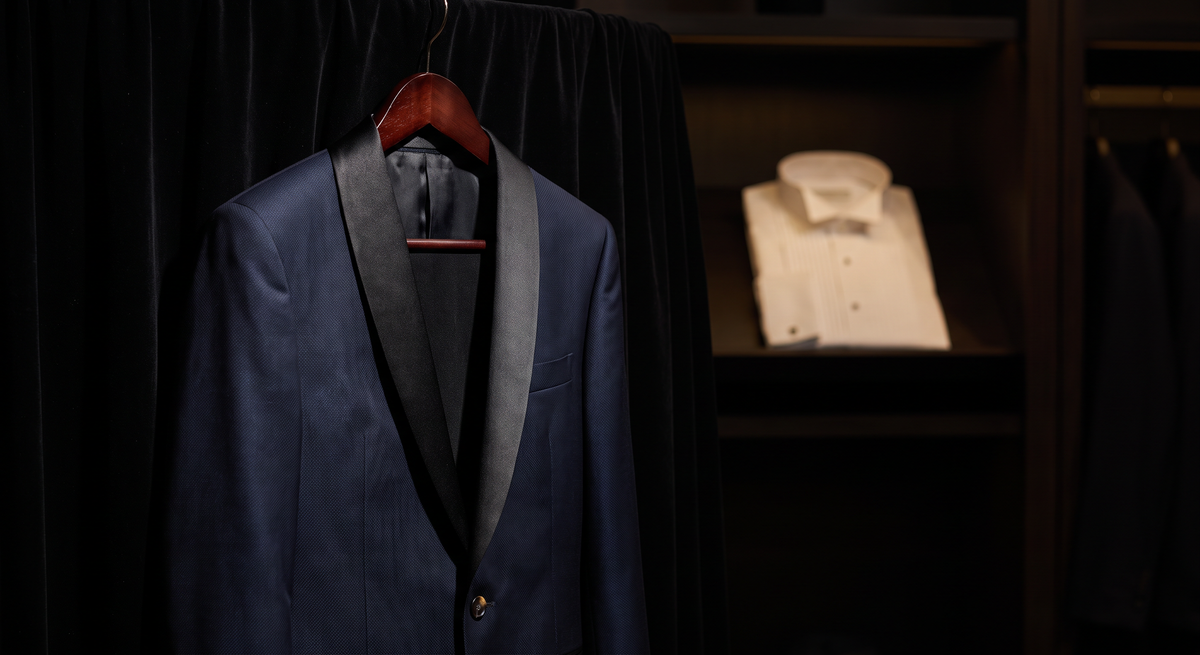 Midnight navy tuxedo with black satin shawl lapels on a wooden hanger