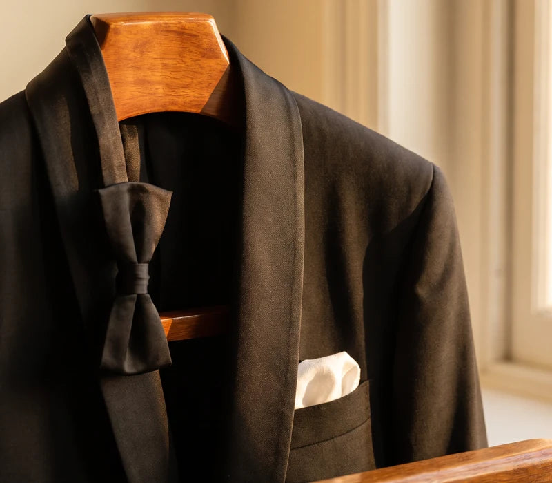 Curved shawl collar on a black dinner jacket in warm window light